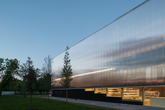 Bâtiment vu d'une rue avec un bardage en plaques de polycarbonate alvéolaire. Le système emboîtable arcoPlus® 549 est résistant aux UV.