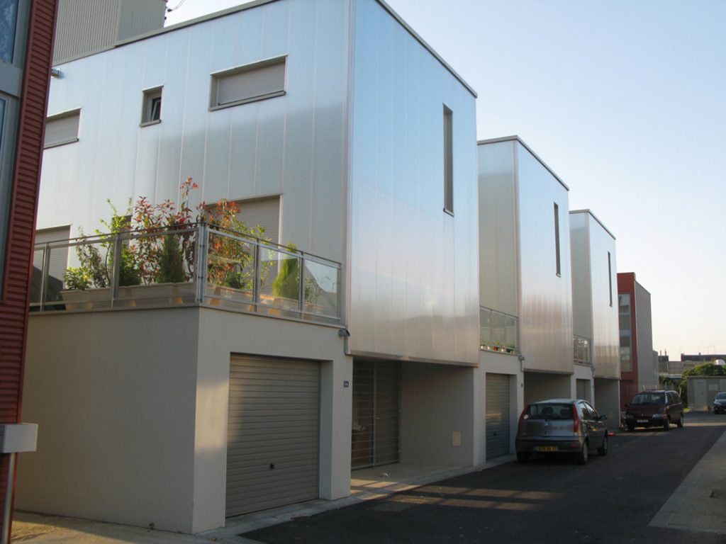 Bâtiment vu d'une rue avec un bardage en plaques de polycarbonate alvéolaire. Le système emboîtable arcoPlus® 549 est résistant aux UV.