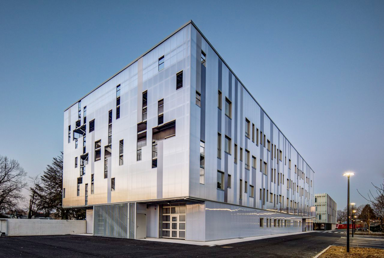Bâtiment vu d'une rue avec un bardage en plaques de polycarbonate alvéolaire. Le système emboîtable arcoPlus® 549 est résistant aux UV.