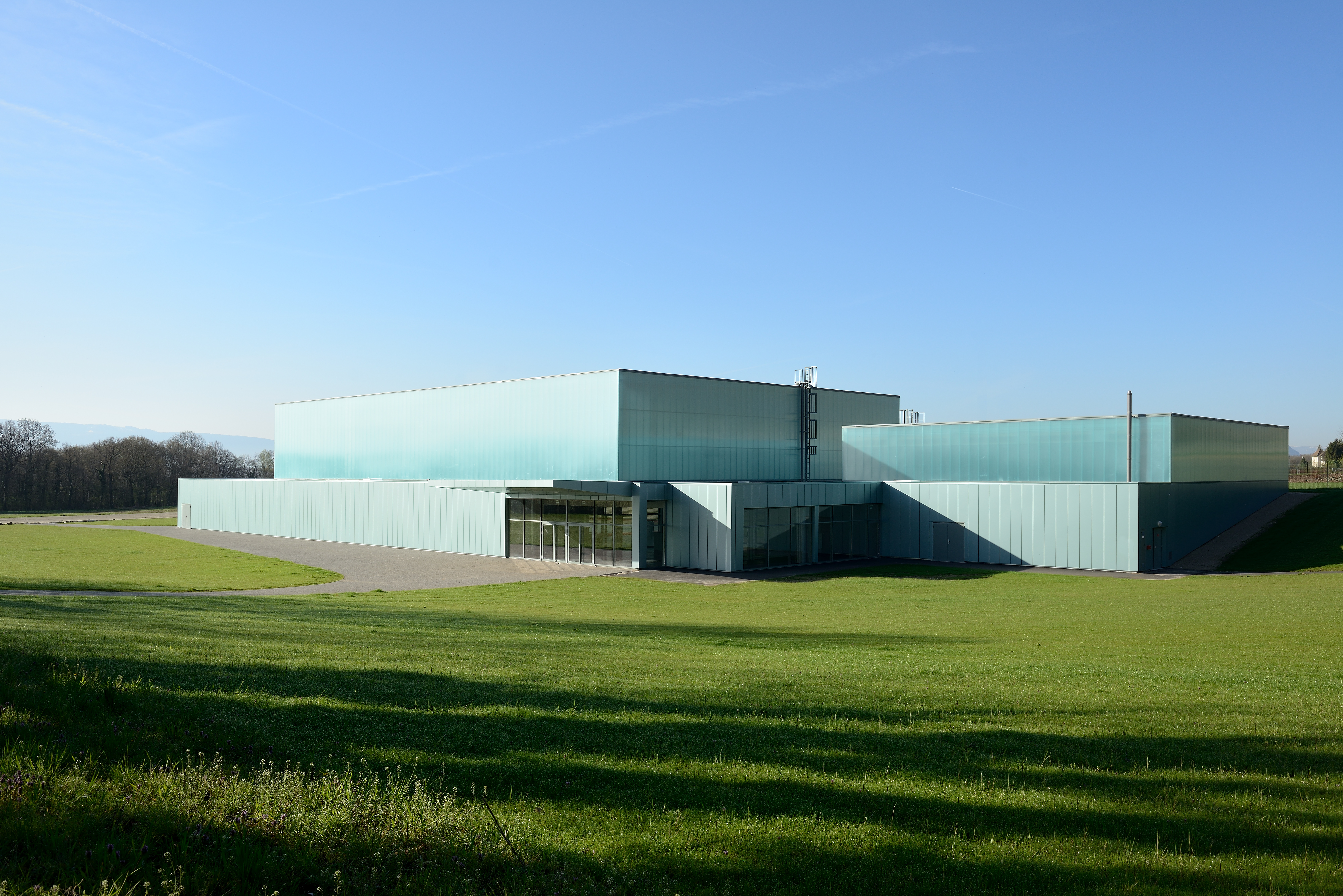 Bâtiment vu d'une rue avec un bardage en plaques de polycarbonate alvéolaire. Le système emboîtable arcoPlus® 549 est résistant aux UV.